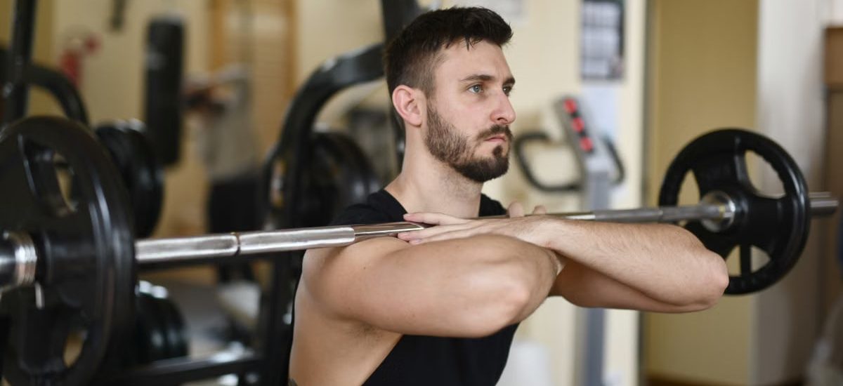 A focused man lifting weights indoors showcasing strength and concentration.